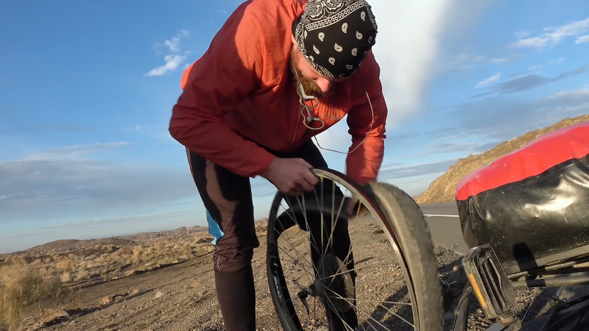 Verplant – Wie zwei Typen versuchen, mit dem Rad nach Vietnam zu fahren. Die beiden befinden sich am Straßenrand auf freiem Land und wechseln ihre Fahrradreifen.