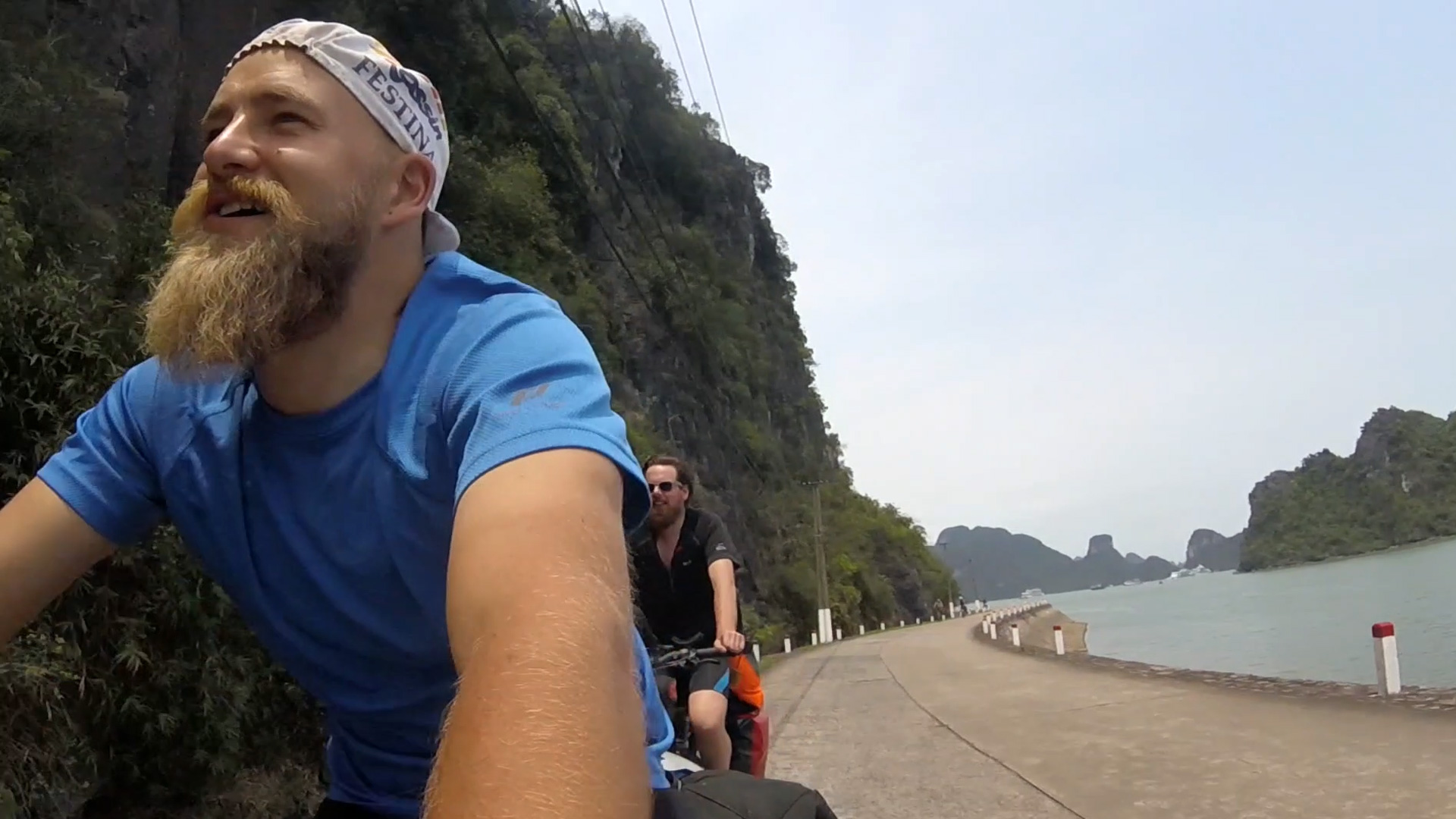 Verplant – Wie zwei Typen versuchen, mit dem Rad nach Vietnam zu fahren. Die Fahrt geht weiter auf einer am Wasser nahe gelegenen Straße.